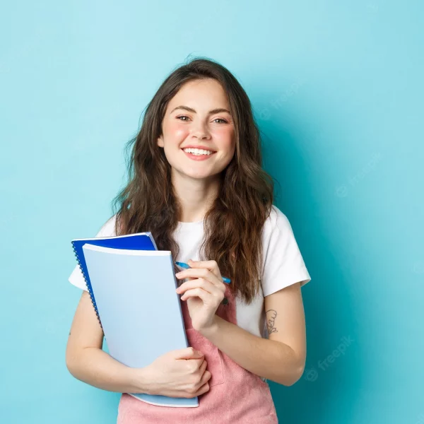 happy-young-female-student-holding-notebooks-from-courses-smiling-camera-standing-spring-clothes-against-blue-background_1258-70161